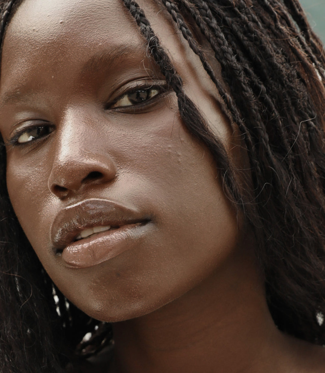Close-up of a person with braided hair and a neutral expression