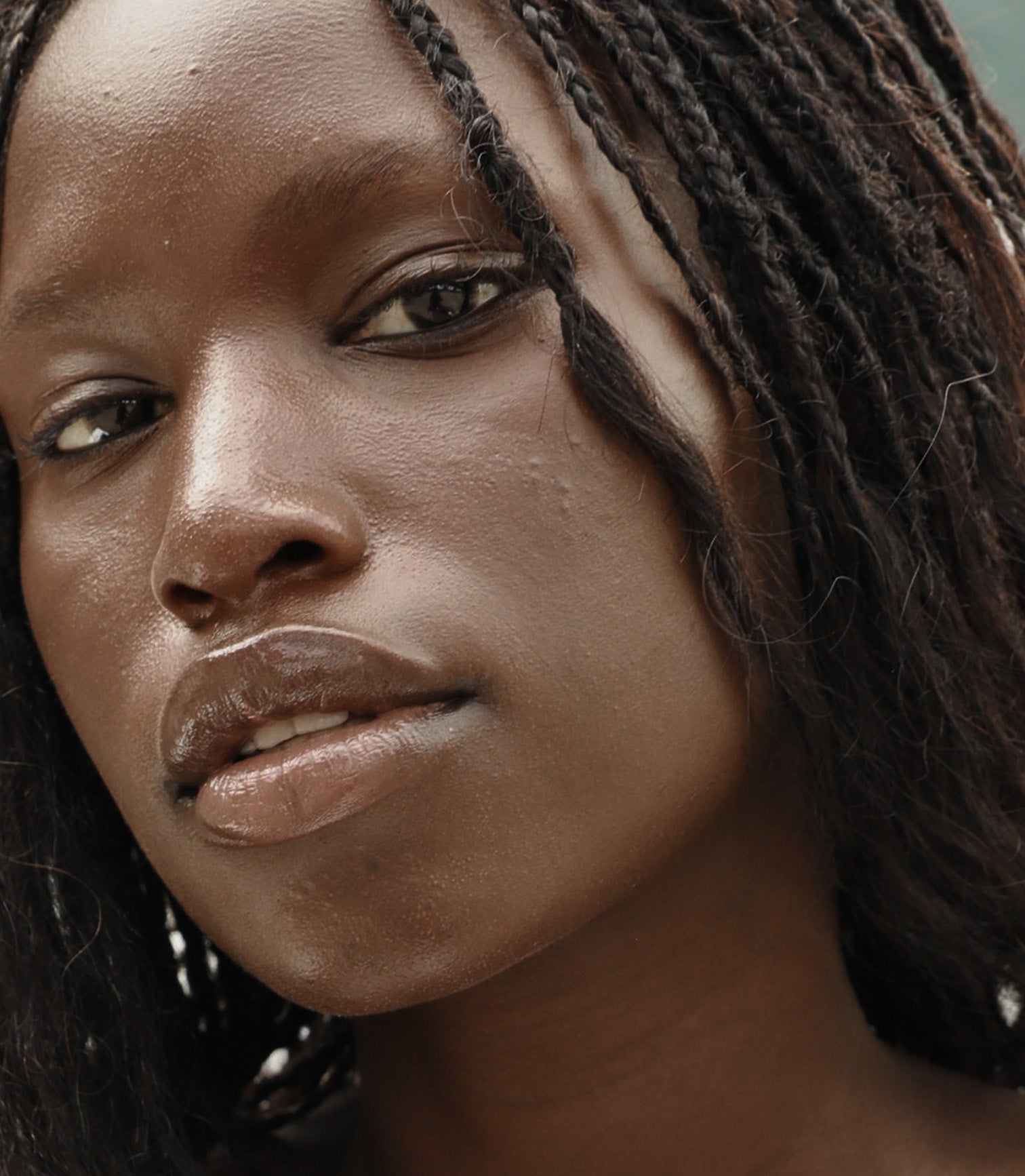 Close-up of a person with braided hair and a neutral expression