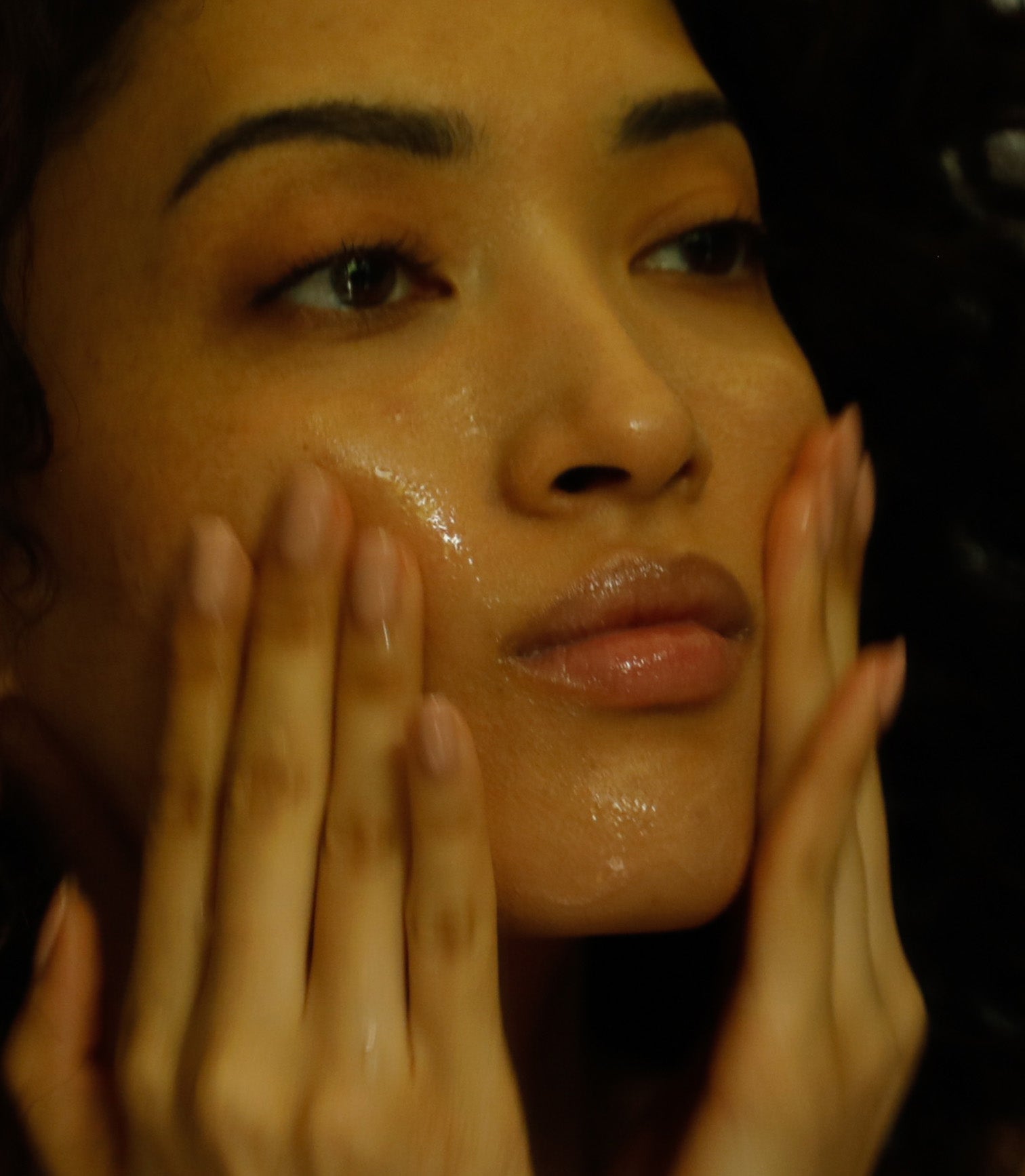 Close-up of a person applying a skincare product to their face.